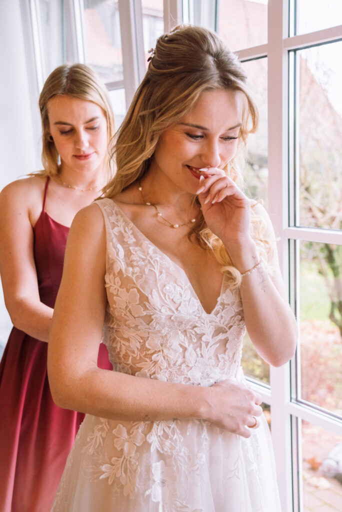 „Emotionale Brautvorbereitung mit Brautjungfer beim Getting Ready am Fenster im Kloster Rebdorf.“