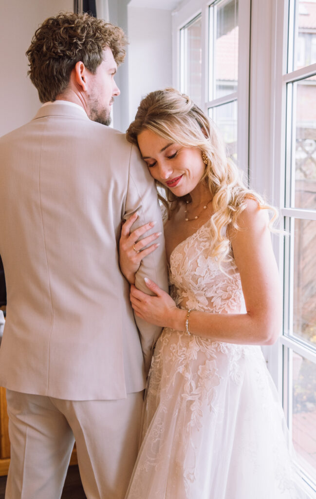 „Emotionales Brautpaar-Portrait beim Fensterlicht während der Hochzeit.“