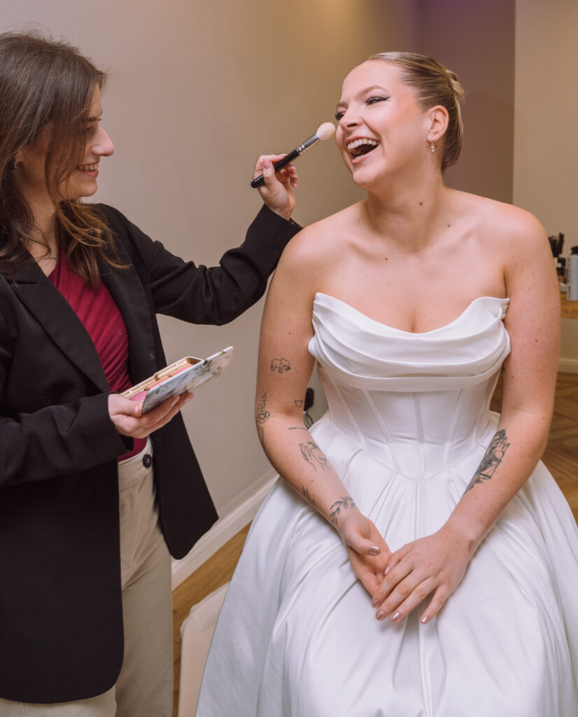 „Modern gekleidete Braut wird beim Getting Ready von Visagistin für die Hochzeit in Ingolstadt geschminkt.“
