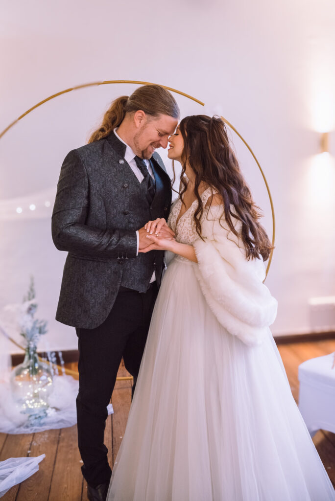 „Brautpaar hält sich liebevoll an den Händen bei einer Winterhochzeit in Bayern, fotografiert von einer Hochzeitsfotografin aus Ingolstadt.“