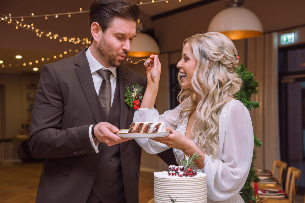„Braut füttert Bräutigam beim Tortenanschnitt während einer Hochzeit in Ingolstadt.“